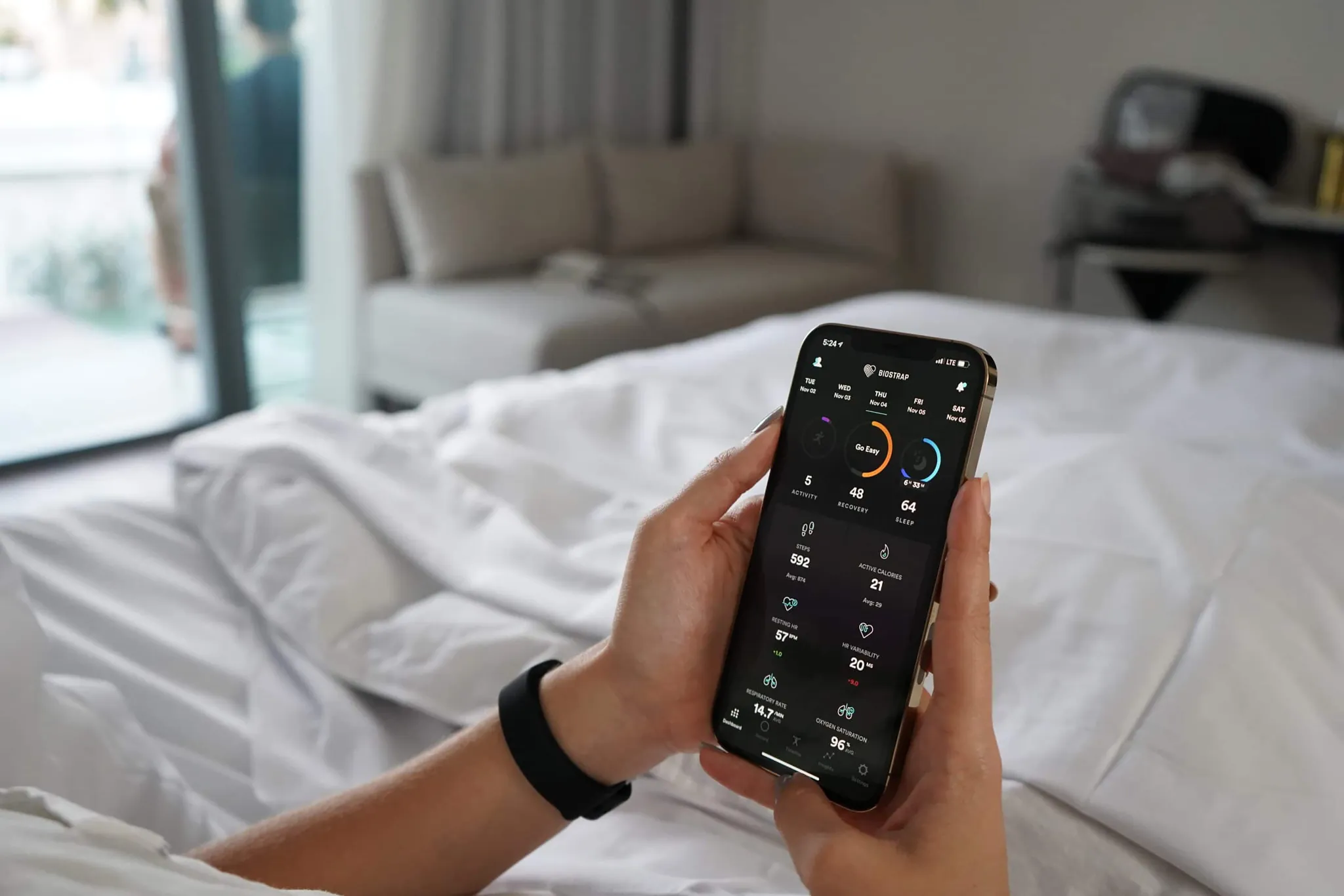 Biostrap health tracking wearable device on wrist alongside mobile app biometrics interface